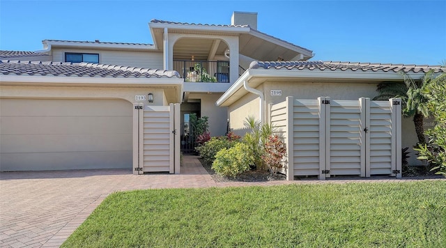 view of front of house with a balcony, a garage, and a front lawn