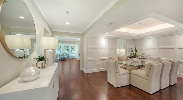 dining area featuring dark wood-type flooring, a raised ceiling, and ornamental molding