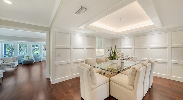 dining room featuring crown molding, a raised ceiling, and dark wood-type flooring