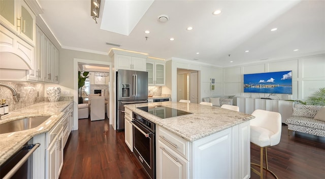 kitchen featuring a center island, black appliances, a kitchen breakfast bar, sink, and white cabinetry