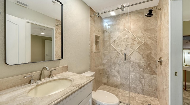 bathroom with a tile shower, vanity, and toilet