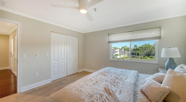 bedroom featuring ceiling fan, a closet, ornamental molding, and light wood-type flooring