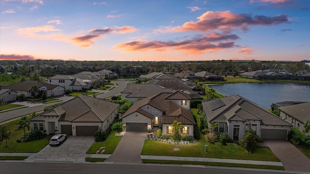 aerial view at dusk with a residential view and a water view