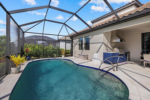 view of swimming pool featuring an outdoor kitchen, a lanai, and a patio area