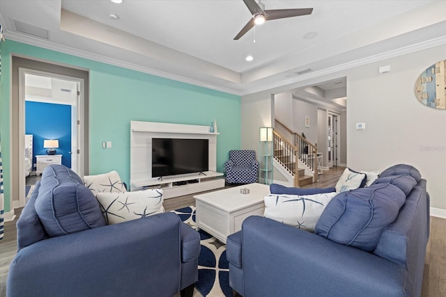 living room with a raised ceiling, ceiling fan, and hardwood / wood-style flooring