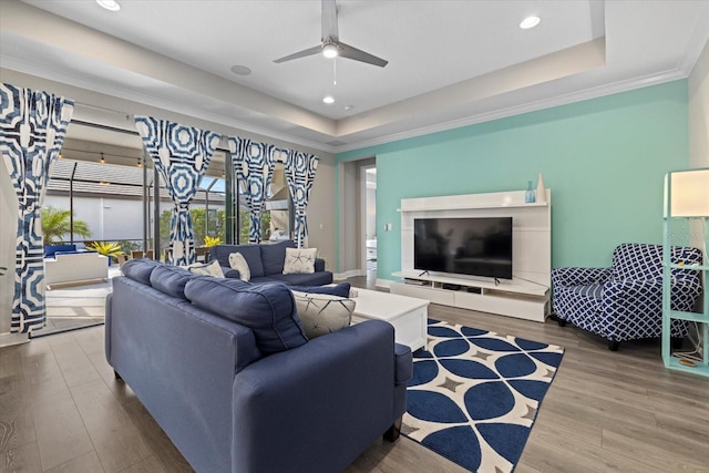 living room featuring a tray ceiling, ceiling fan, and wood-type flooring