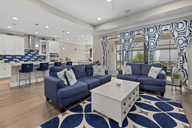 living room with crown molding, light hardwood / wood-style flooring, and sink