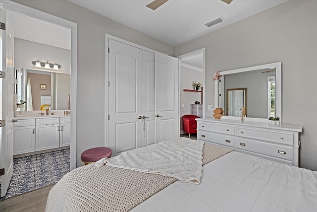 bedroom featuring ceiling fan, sink, connected bathroom, light hardwood / wood-style floors, and a closet