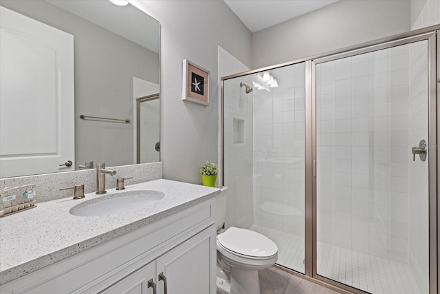 bathroom with a shower with door, vanity, and toilet