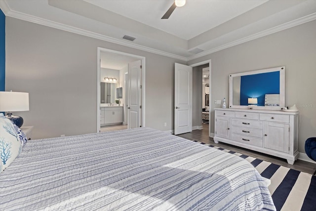 bedroom featuring ceiling fan, dark hardwood / wood-style flooring, ensuite bathroom, and a tray ceiling