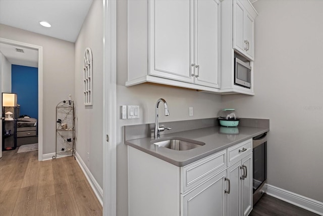 kitchen featuring white cabinets, sink, beverage cooler, and light hardwood / wood-style flooring