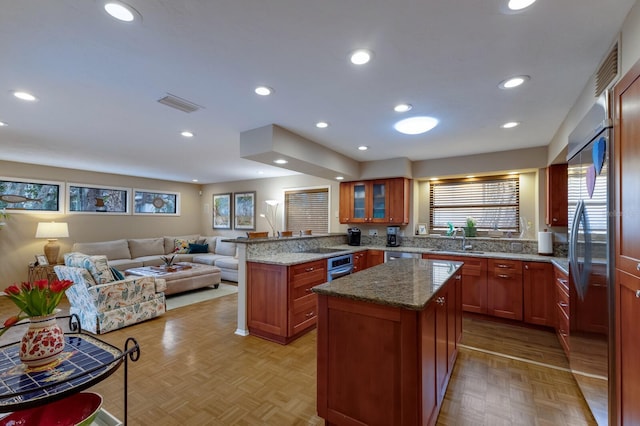 kitchen featuring light stone countertops, a kitchen island, sink, kitchen peninsula, and light parquet floors