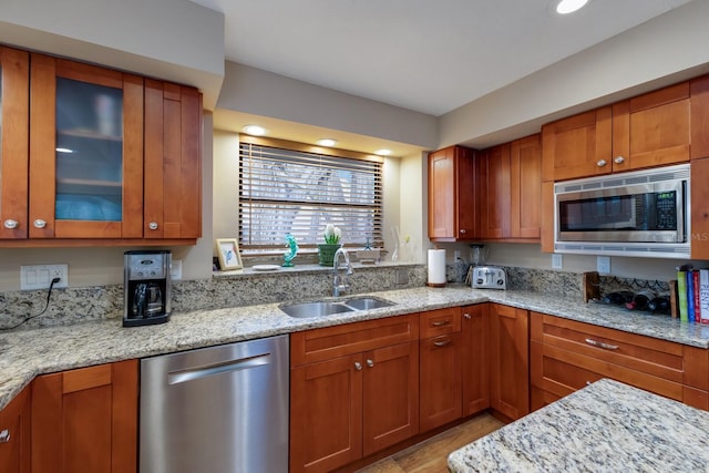 kitchen featuring appliances with stainless steel finishes, light stone counters, and sink