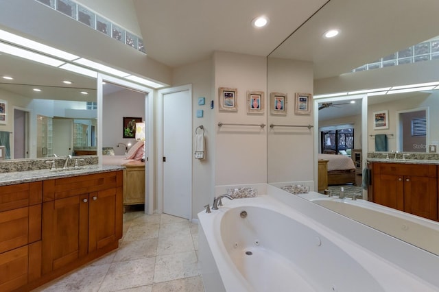 bathroom with ceiling fan, vanity, vaulted ceiling, and a bathing tub