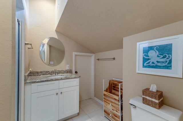 bathroom with a textured ceiling, toilet, vanity, and tile patterned flooring