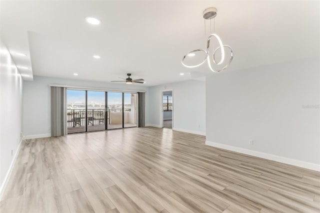 unfurnished living room with ceiling fan with notable chandelier and light hardwood / wood-style flooring