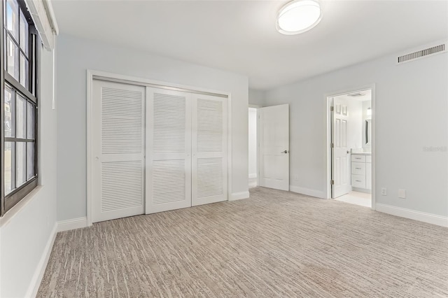 unfurnished bedroom with a closet and ensuite bath