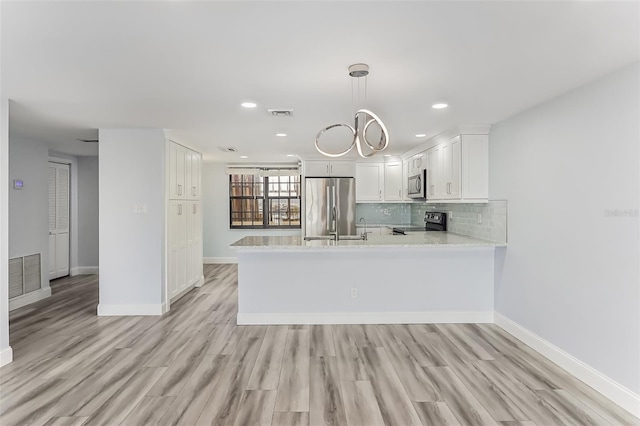 kitchen with decorative light fixtures, kitchen peninsula, decorative backsplash, white cabinetry, and stainless steel appliances