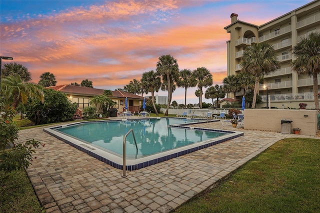 pool at dusk with a patio area