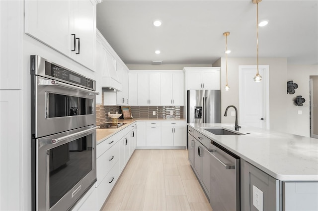 kitchen with pendant lighting, sink, white cabinets, and appliances with stainless steel finishes