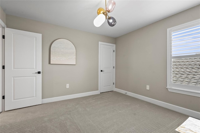 spare room featuring an inviting chandelier and light colored carpet