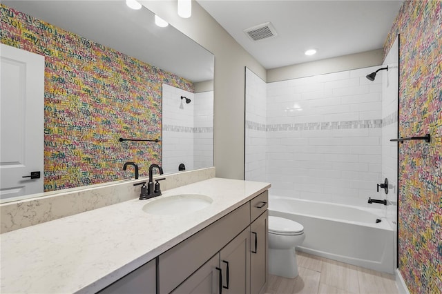 full bathroom featuring tiled shower / bath combo, vanity, and toilet