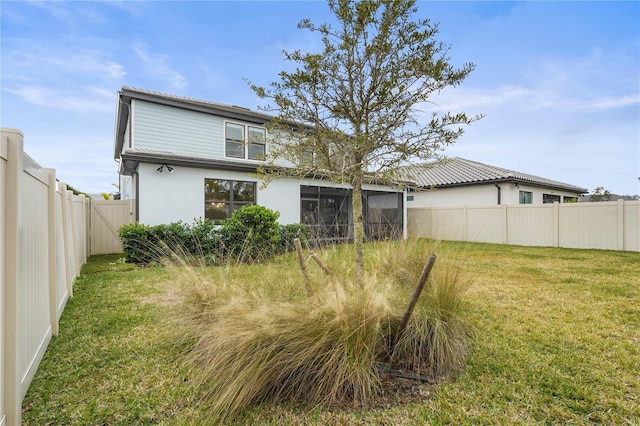 rear view of property featuring a lawn and a sunroom