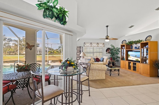 dining space with ceiling fan, lofted ceiling, and light tile patterned floors