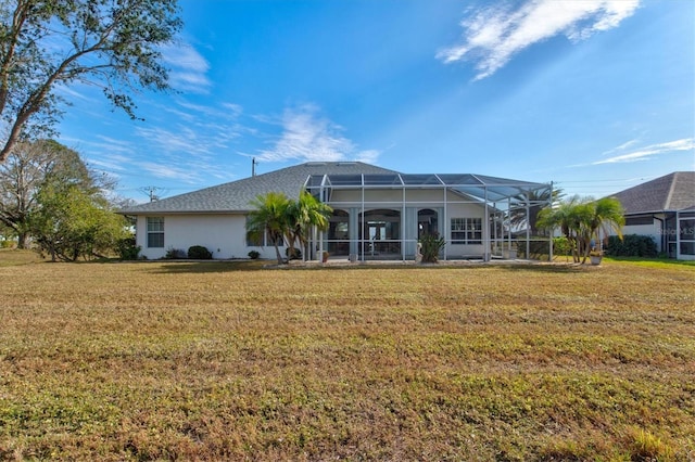 rear view of house featuring glass enclosure and a lawn