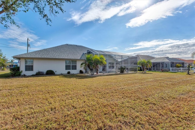 rear view of property featuring a yard and glass enclosure