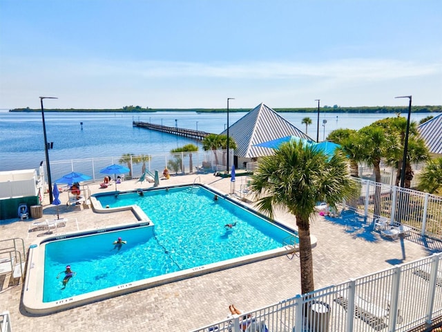 view of swimming pool featuring a water view and a patio