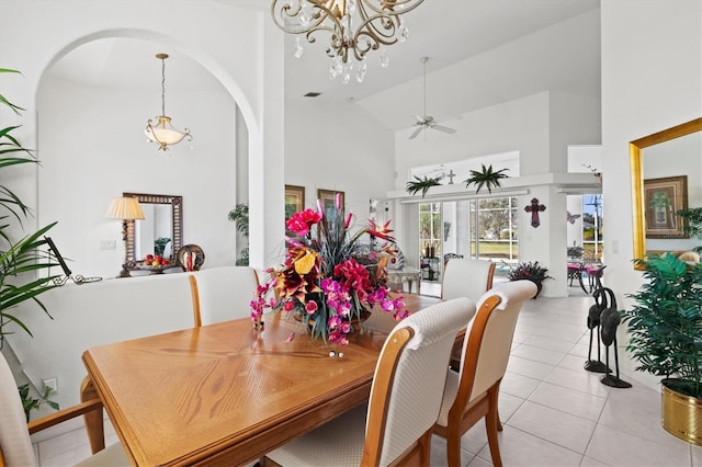 dining room with ceiling fan with notable chandelier, high vaulted ceiling, and light tile patterned floors