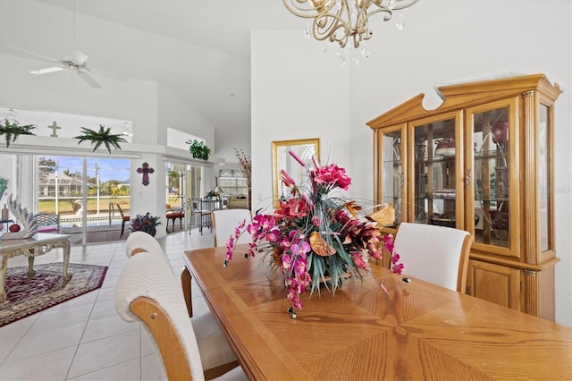 dining area featuring ceiling fan with notable chandelier, light tile patterned floors, french doors, and a high ceiling