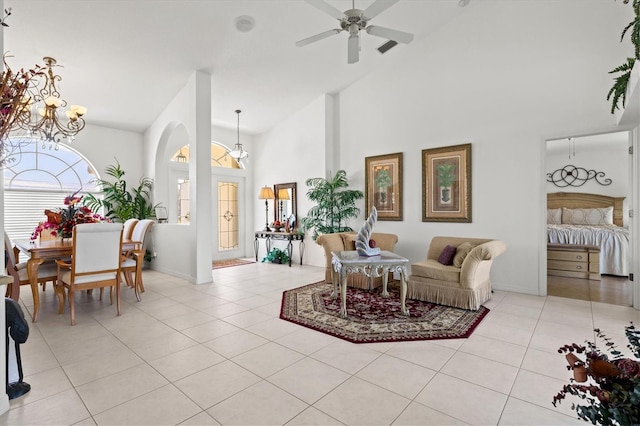 living room with light tile patterned flooring, ceiling fan with notable chandelier, and high vaulted ceiling