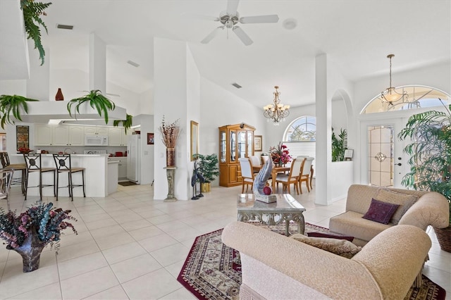 living room featuring light tile patterned flooring, a towering ceiling, and ceiling fan with notable chandelier