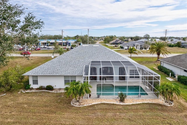 rear view of house featuring a yard and glass enclosure