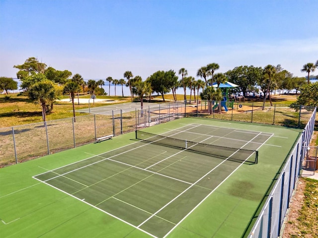 view of sport court with basketball hoop and a playground