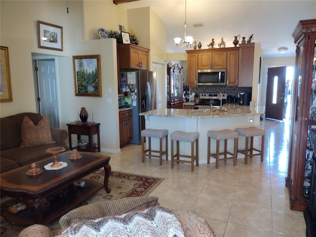 kitchen with hanging light fixtures, a notable chandelier, backsplash, kitchen peninsula, and appliances with stainless steel finishes