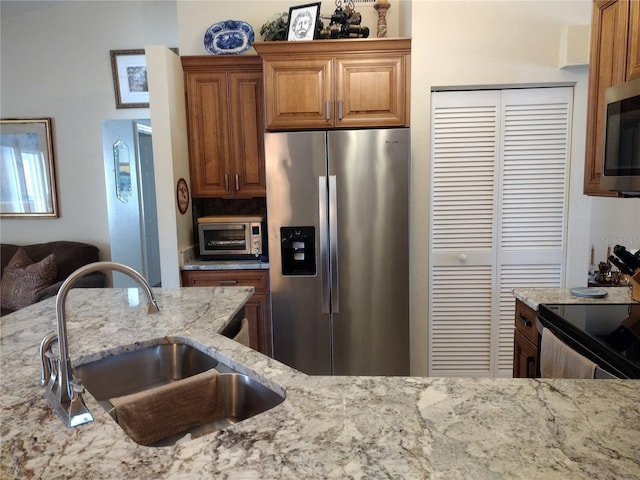 kitchen featuring light stone counters, sink, and appliances with stainless steel finishes