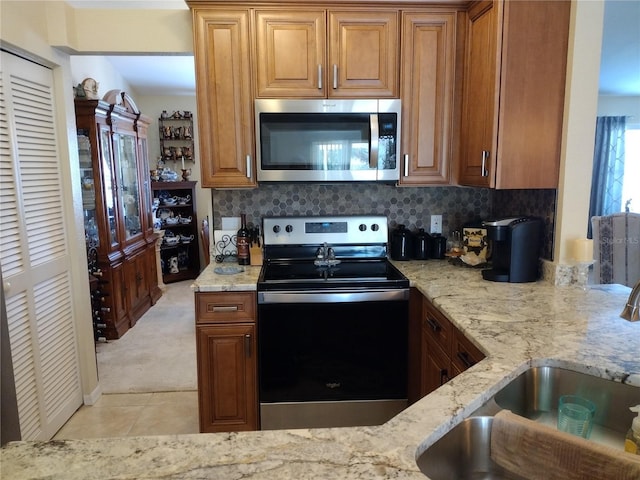 kitchen featuring appliances with stainless steel finishes, tasteful backsplash, light stone counters, and sink