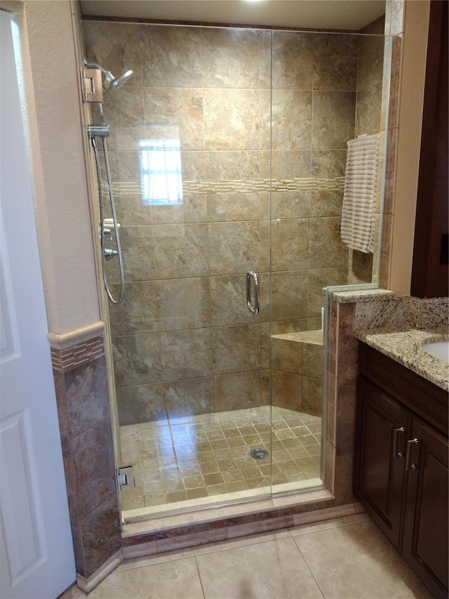 bathroom with tile patterned flooring, vanity, and a shower with door