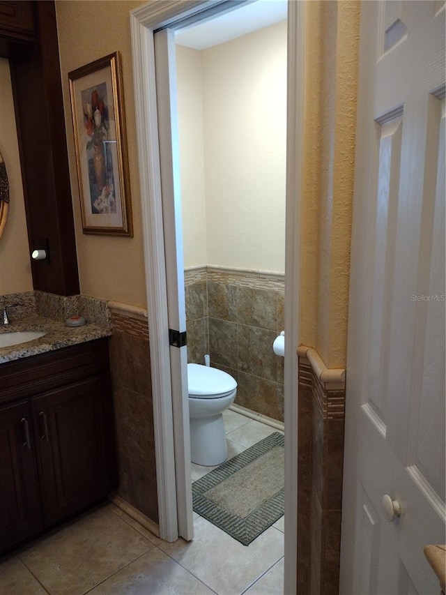 bathroom featuring tile patterned flooring, vanity, tile walls, and toilet