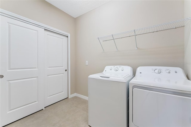 laundry room with a textured ceiling, light tile patterned floors, and washing machine and clothes dryer