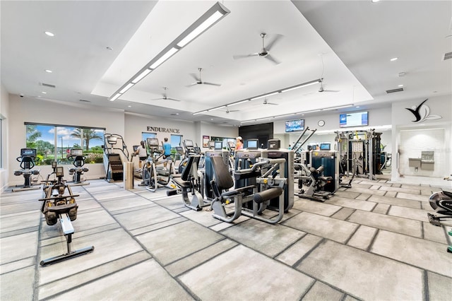 workout area featuring ceiling fan, track lighting, and a tray ceiling