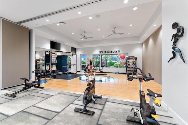 gym featuring ceiling fan, hardwood / wood-style floors, and a tray ceiling