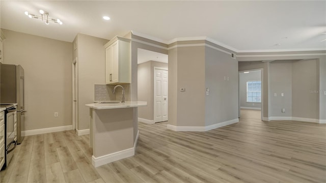 kitchen with crown molding, sink, backsplash, light wood-type flooring, and white cabinetry