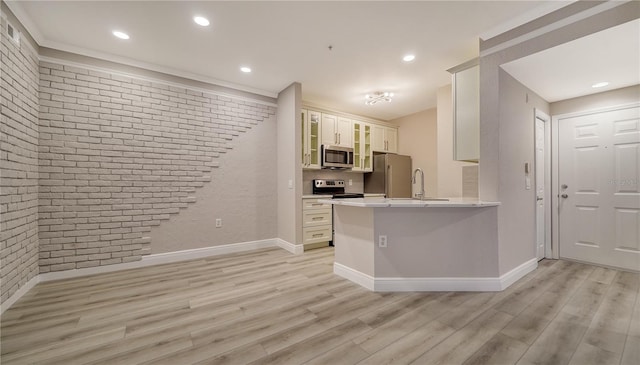 kitchen featuring appliances with stainless steel finishes, white cabinetry, brick wall, light wood-type flooring, and kitchen peninsula