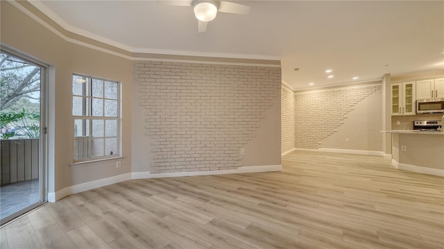 interior space with ceiling fan, brick wall, crown molding, and light wood-type flooring