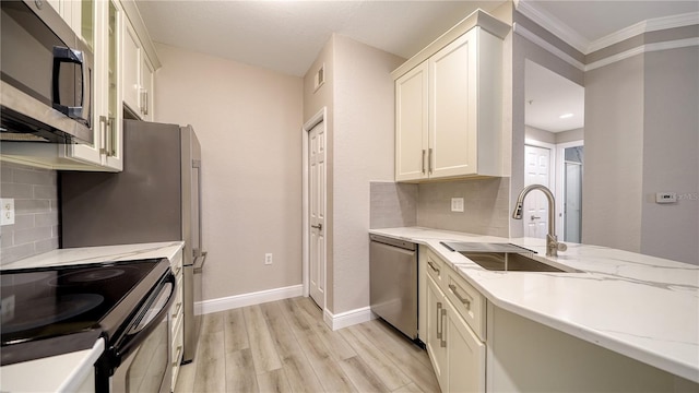 kitchen featuring light stone countertops, appliances with stainless steel finishes, decorative backsplash, sink, and ornamental molding