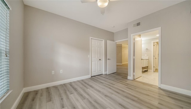 unfurnished bedroom featuring ceiling fan, ensuite bath, and light wood-type flooring